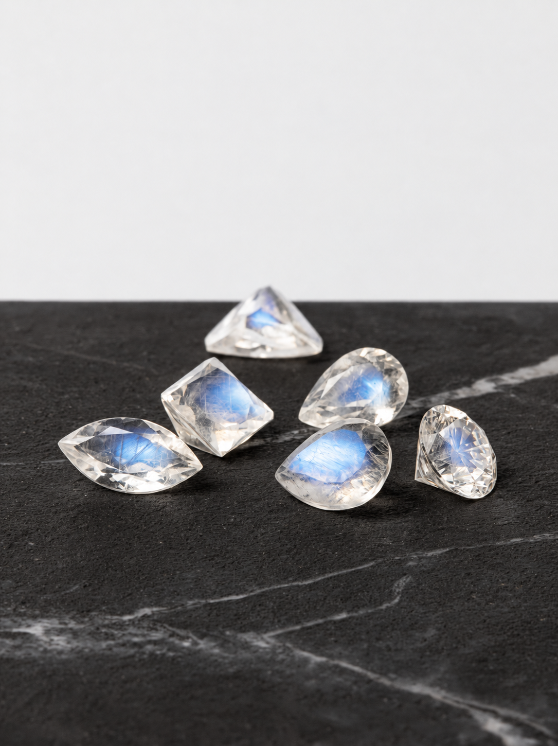Faceted moonstones arranged on a dark marble surface