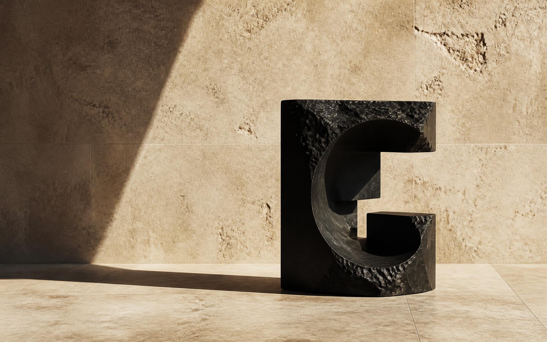 Carved black stone object on warm limestone in hard Mediterranean light